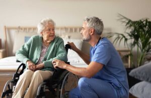 Older adult speaking with a caregiver in a bright assisted living apartment.